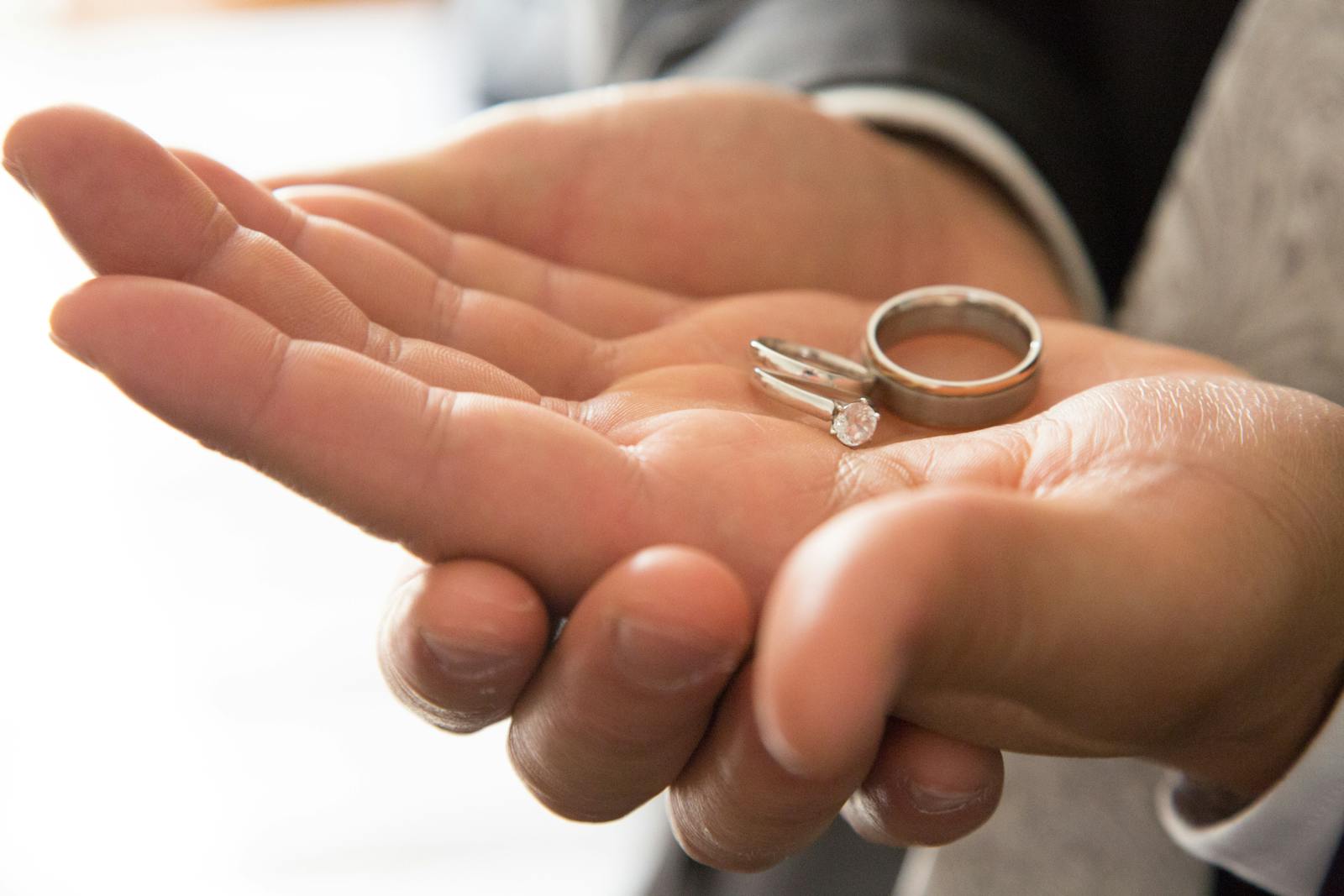 Detail shot of hands with wedding rings in soft light
